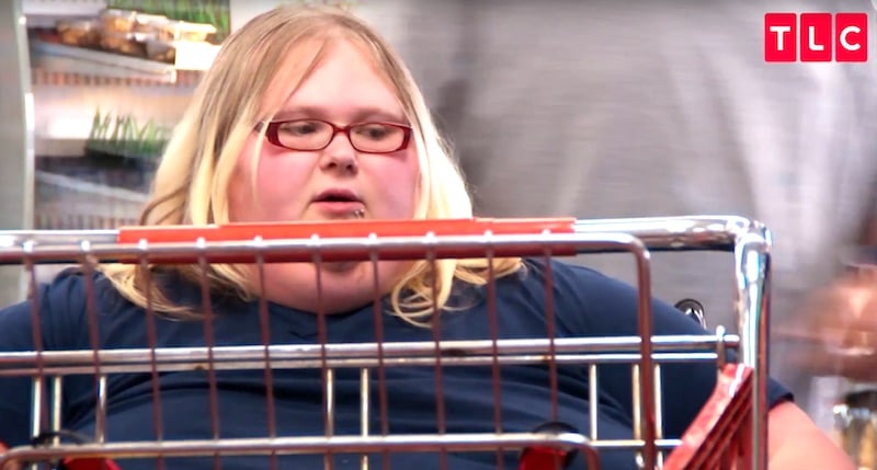 Nicole behind a trolley as she gets pushed around the store in her chair