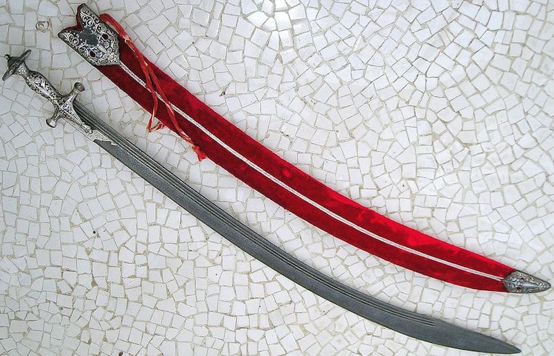 A talwar sword lying next to its red sheath