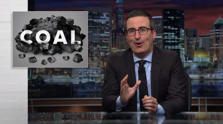 John Oliver talks to the camera with a picture of coal on the screen behind him