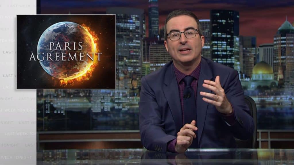 John Oliver on Last Week Tonight, with a picture of a flaming Earth and the words 'Paris Agreement' behind him