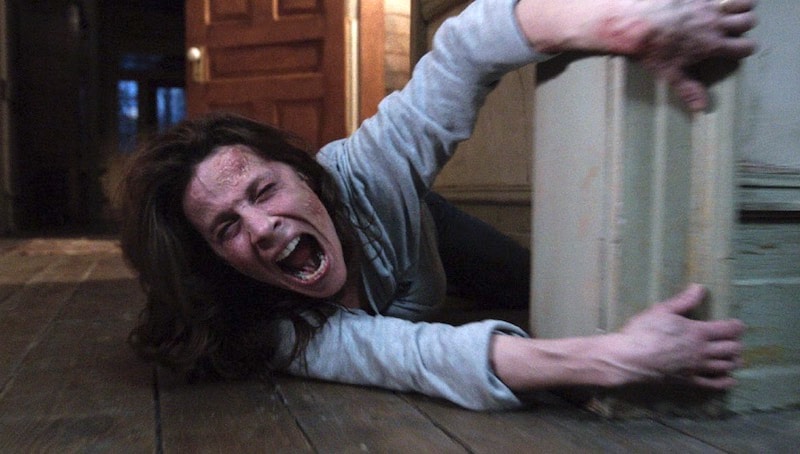 Lili Taylor as Carolyn Perron screaming as she's dragged along the floor in a scene from The Conjuring