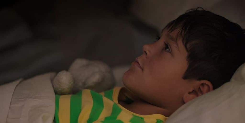 Ethan Kent as Ralph lying on a bed in Room 104