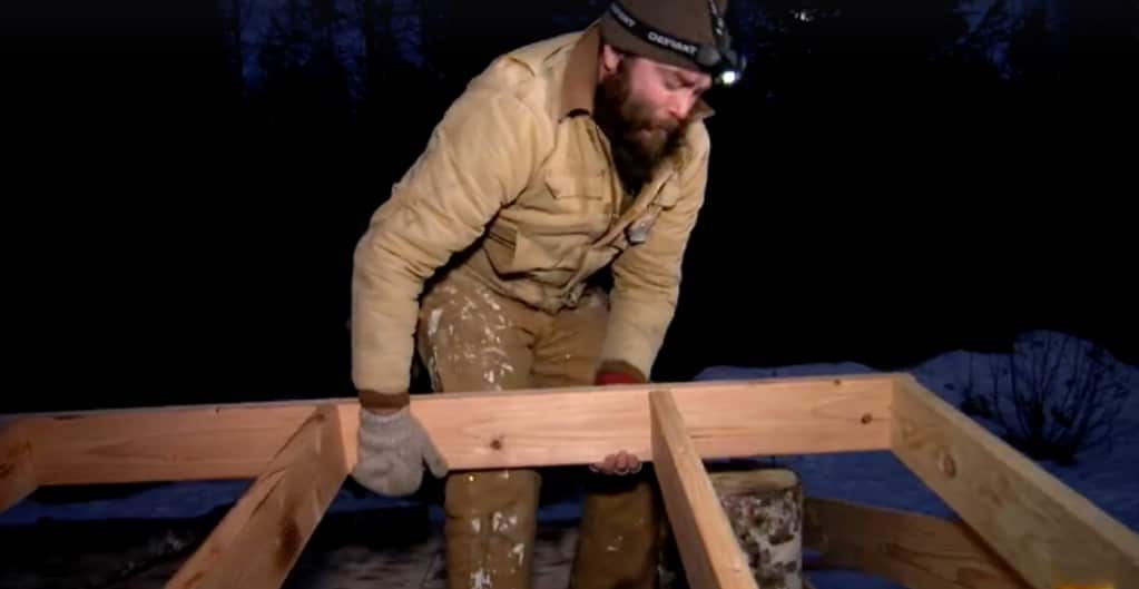 Morgan moves a wooden frame as he builds house