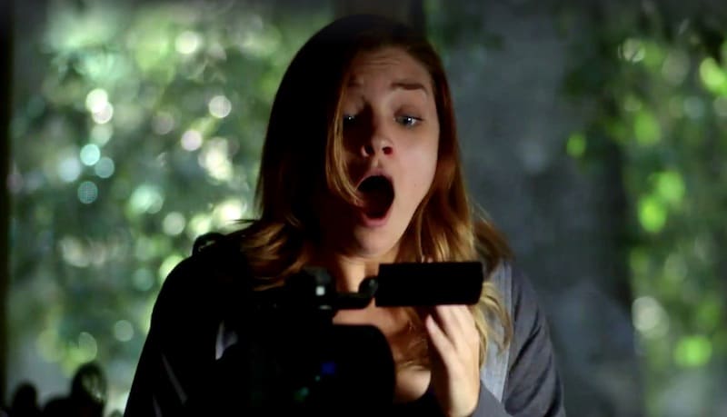 A scene from Evil Things showing a woman screaming at something she sees on a camcorder