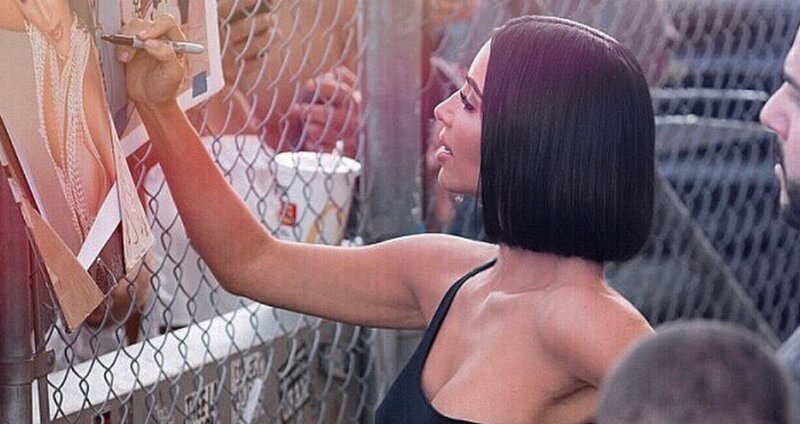 Kim Kardashian signs photos of herself before heading inside a California state prison