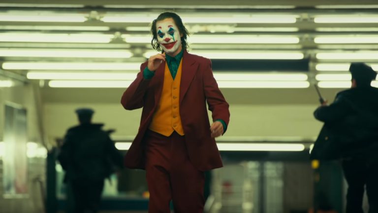 Joaquin Phoenix walking through subway in full Joker makeup.