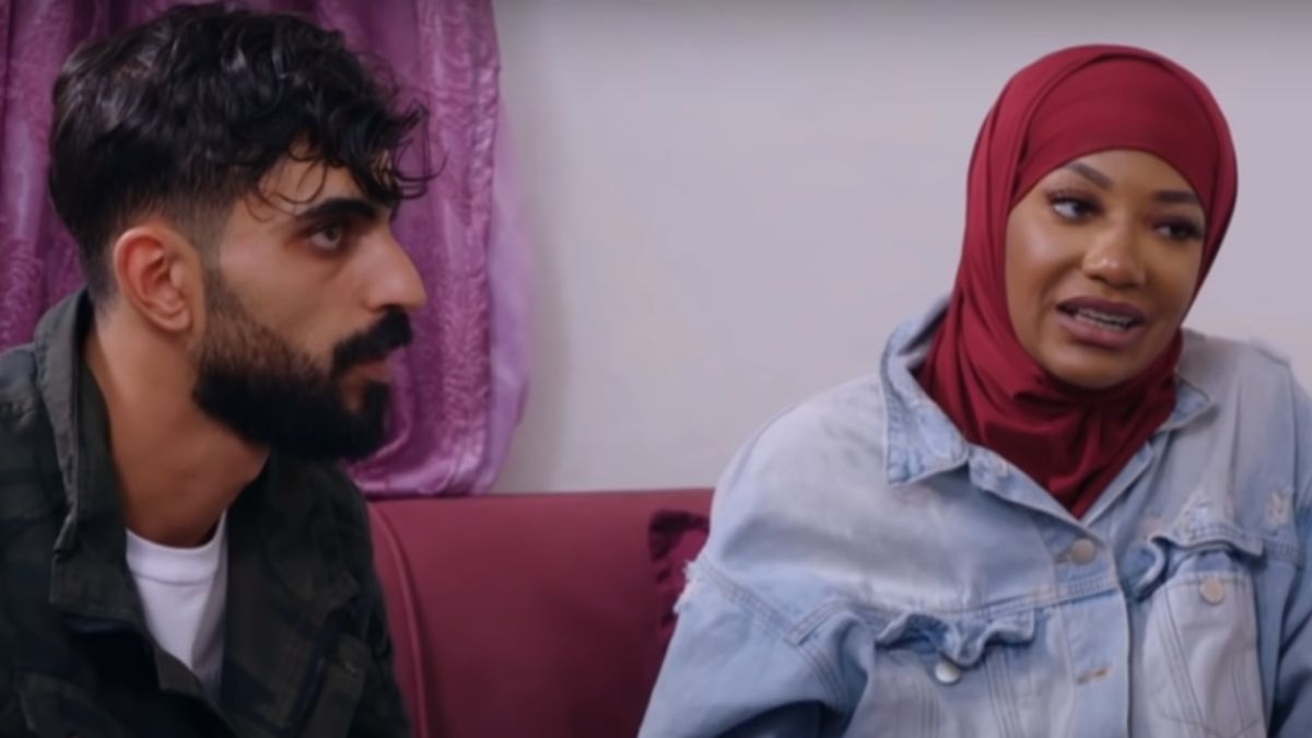 Yazan talks to Brittany while she sits on the couch in a hijab
