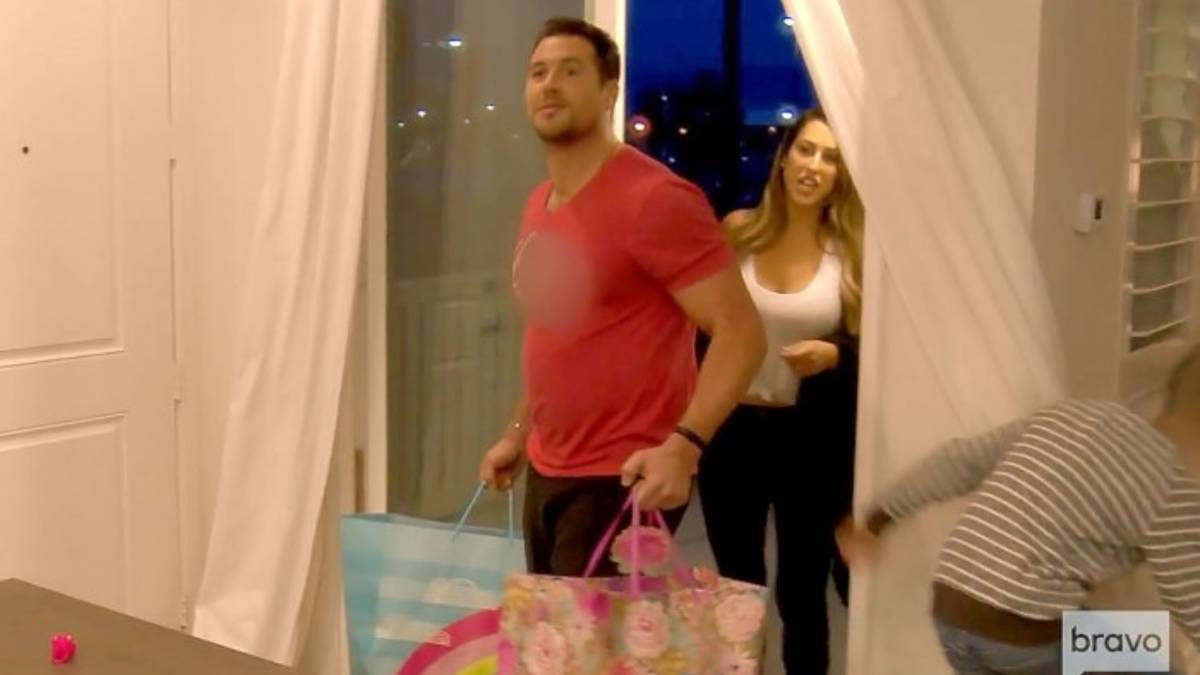 Matt Kirschenheiter and his girlfriend walk through a door holding gifts.