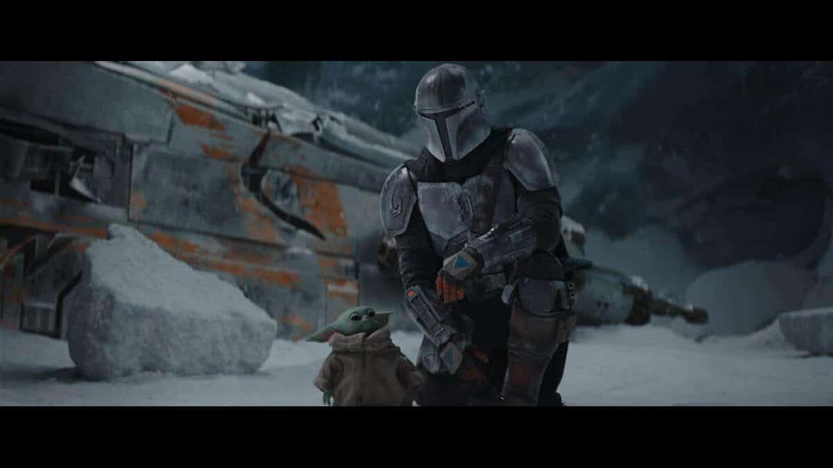 The Mandalorian knees in the snow next to Grogu with his ship in the background