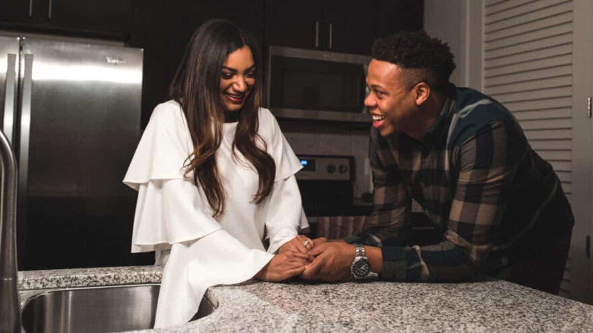 Mia and Tristan hold hands in the kitchen