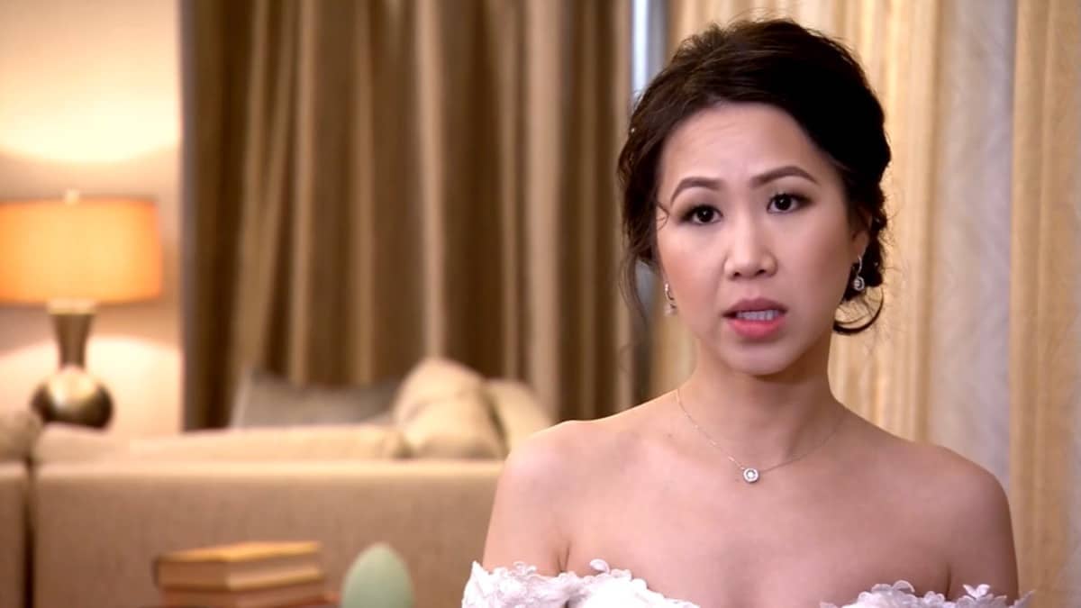 Bao wears earrings and a wedding dress while looking directly at the camera