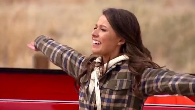 Katie Thurston spreads her arms by a red truck