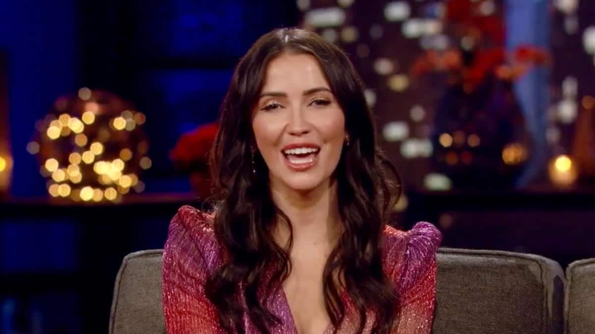 Kaitly Bristowe smiles while sitting on a couch