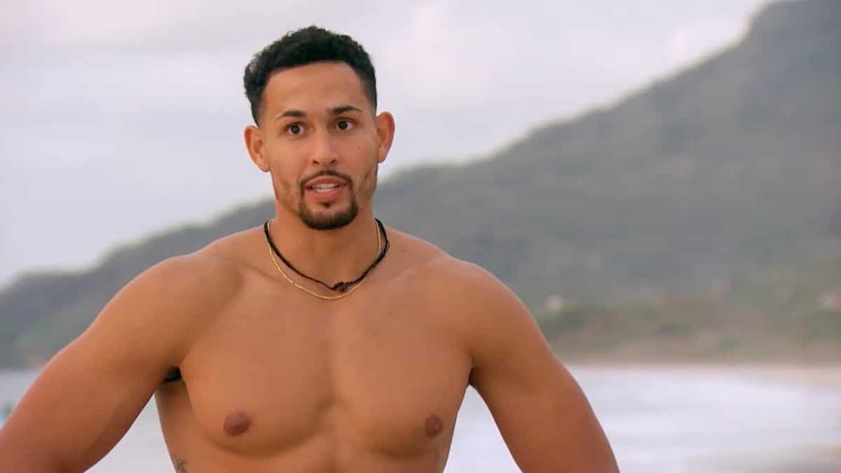 Thomas Jacobs stands shirtless on the beach