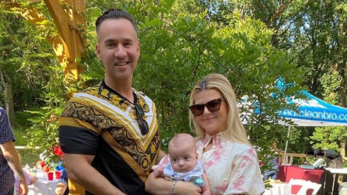 Mike Sorrentino posing with his new baby Romeo and his wife Lauren at an outdoor party