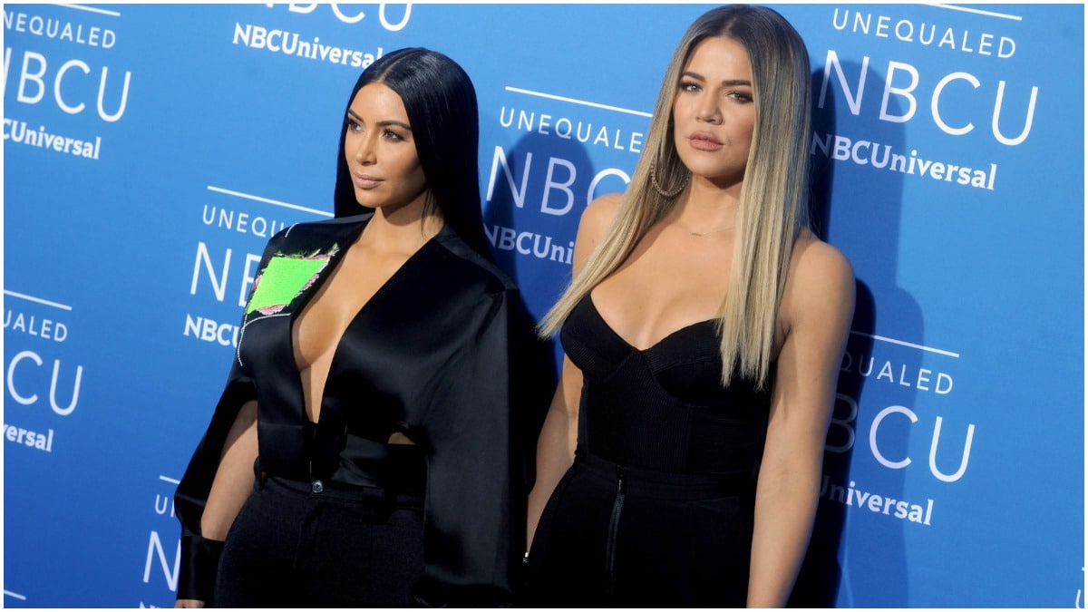 Kim Kardashian West and Khloé Kardashian wearing black outfits at a red carpet event.