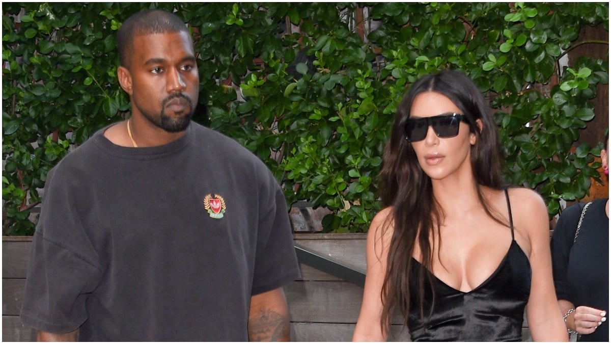 Kanye West walking with Kim Kardashian outside.