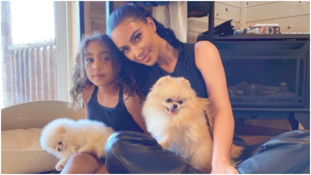 North West and Kim Kardashian posing for a photo while holding their dogs.