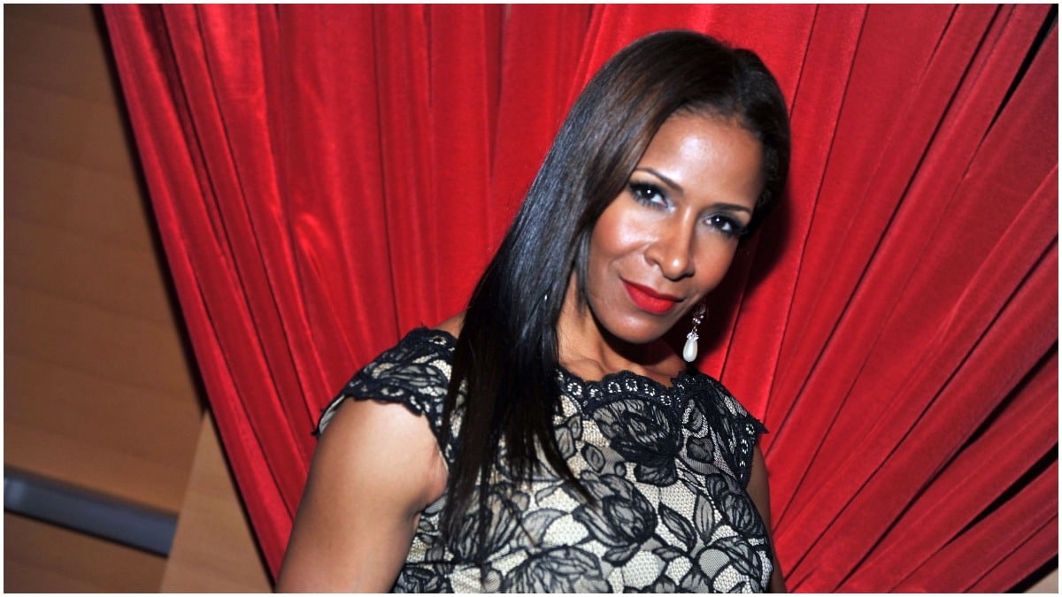 Sheree Whitfield posing in a grey top and red lipstick.