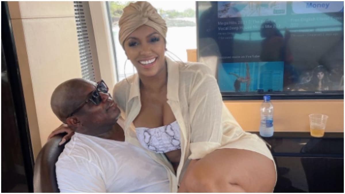 Simon Guobadia sitting down while Porsha Williams sits on his lap.