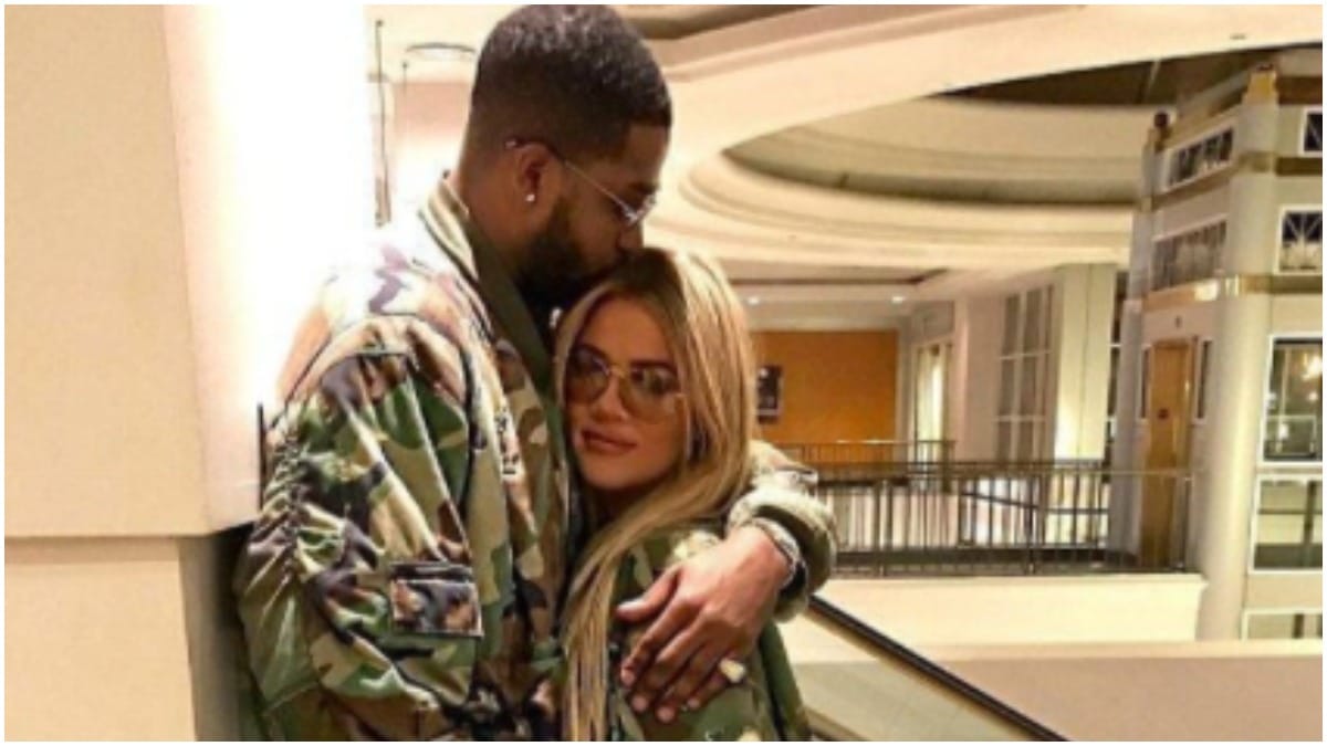 Tristan Thompson kissing Khloe Kardashian's forehead while they're wearing matching camo jackets.