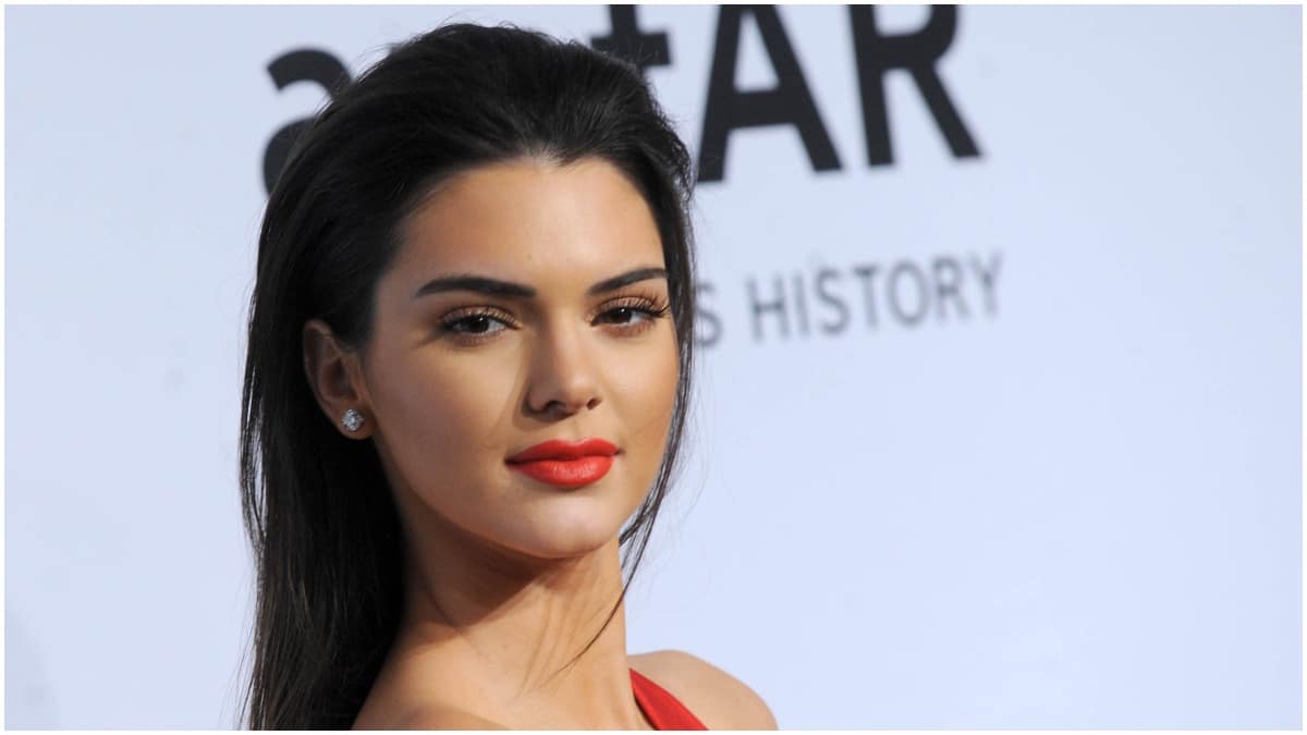 Kendall Jenner wearing red lipstick and a dress on the red carpet.