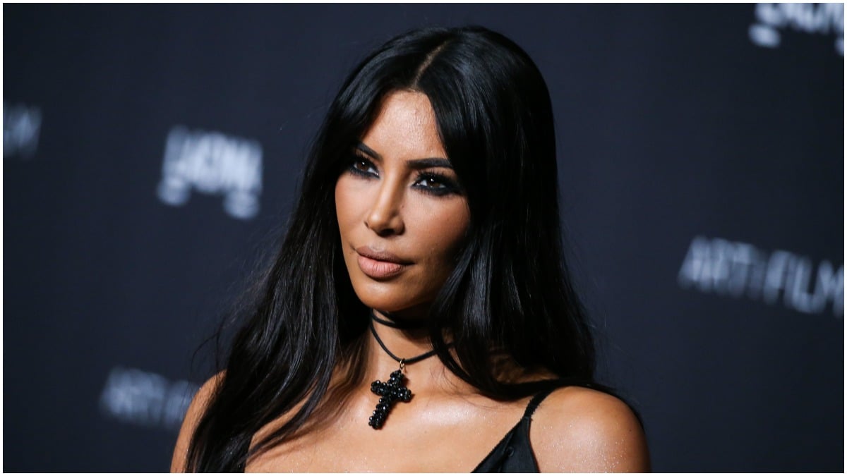 Kim Kardashian posing in a black dress with a cross necklace.