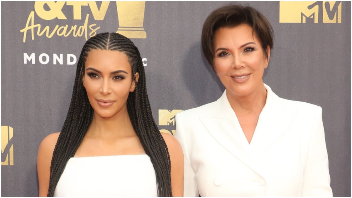 Kim Kardashian and Kris Jenner wearing white outfits on the red carpet.