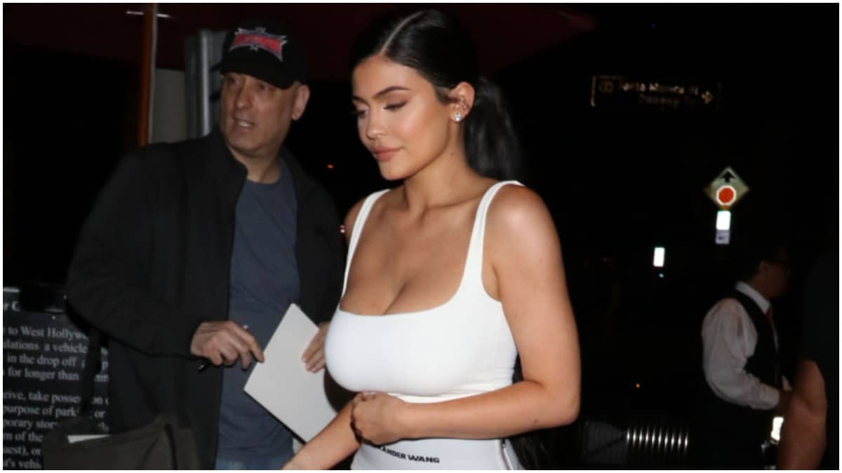 Kylie Jenner walking outside in a white tank top.