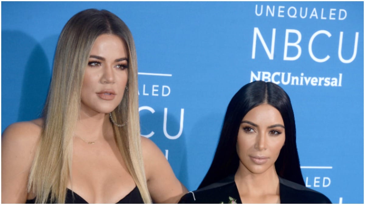 Khloe Kardashian and Kim Kardashian posing on the red carpet