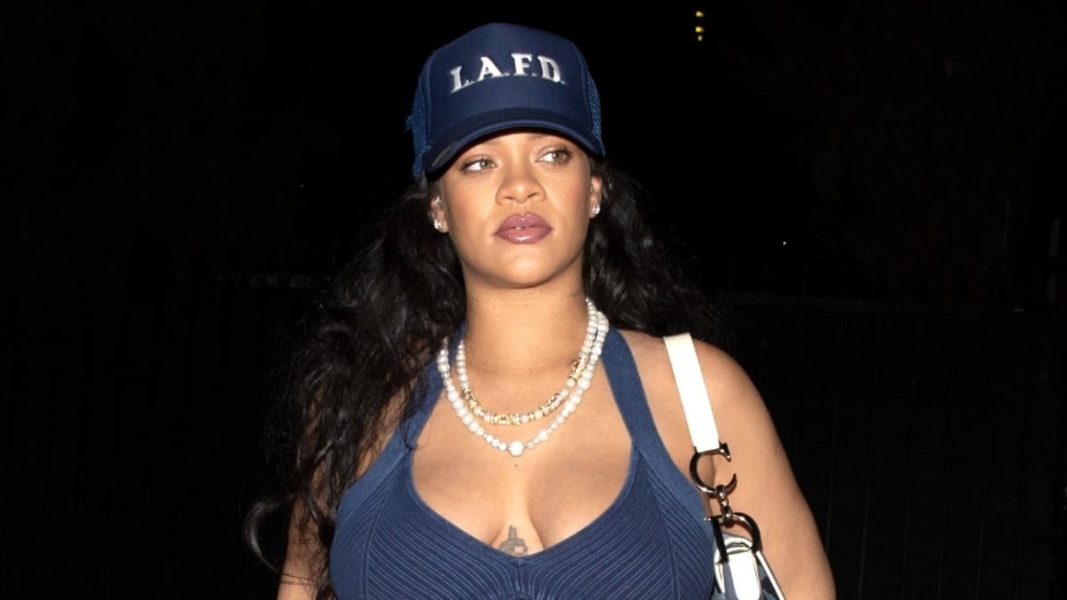 Rihanna shows off bare baby bump in a sports bra and low-slung skirt.