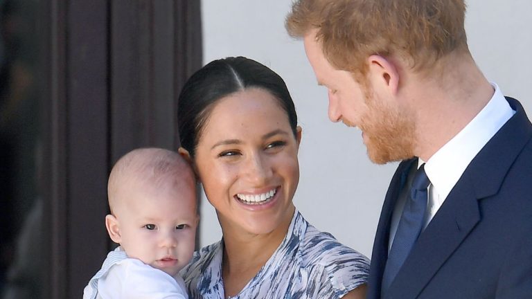 Meghan Markle holds her son Archie with Prince Harry while smiling