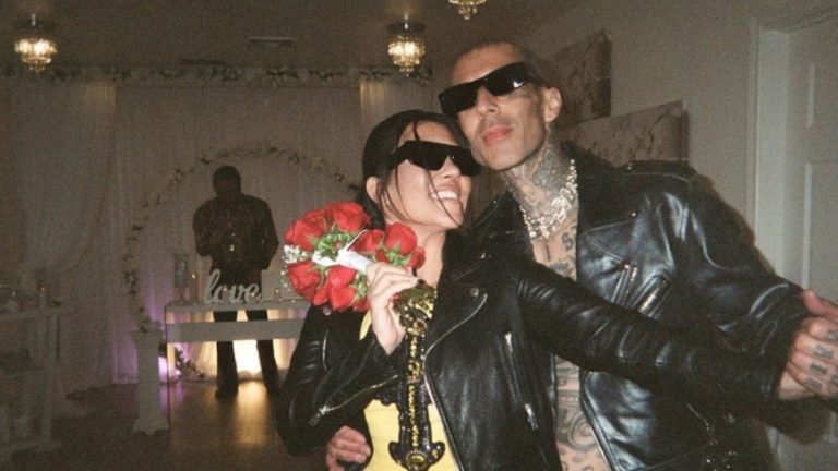 Kourtney Kardashian and Travis Barker smile at the camera with glasses on after getting married in Las Vegas