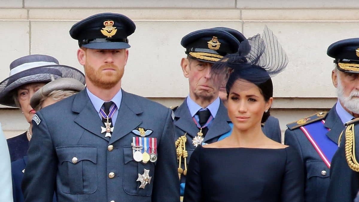 Prince Harry in uniform and Meghan Markle in a black dress and black hat