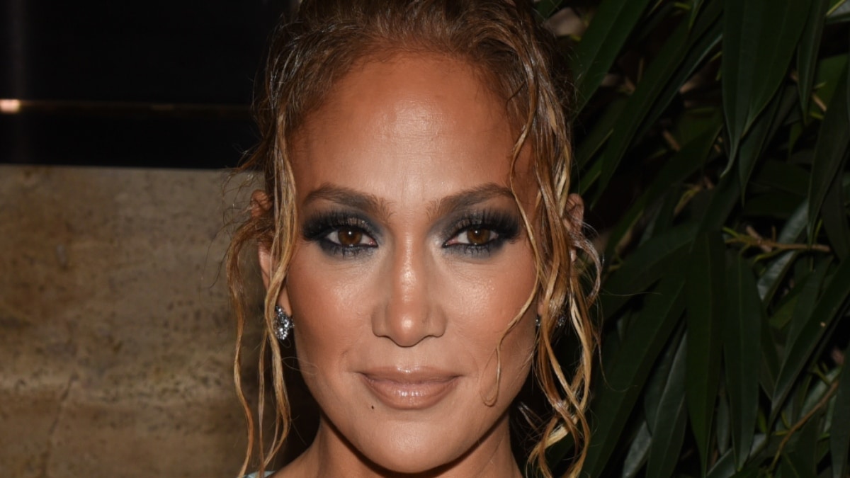 A close-up photo of Jennifer Lopez smiling in smokey eye makeup.