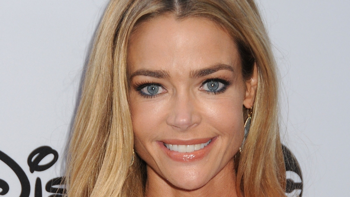 Denise Richards smiles at the camera on the red carpet.