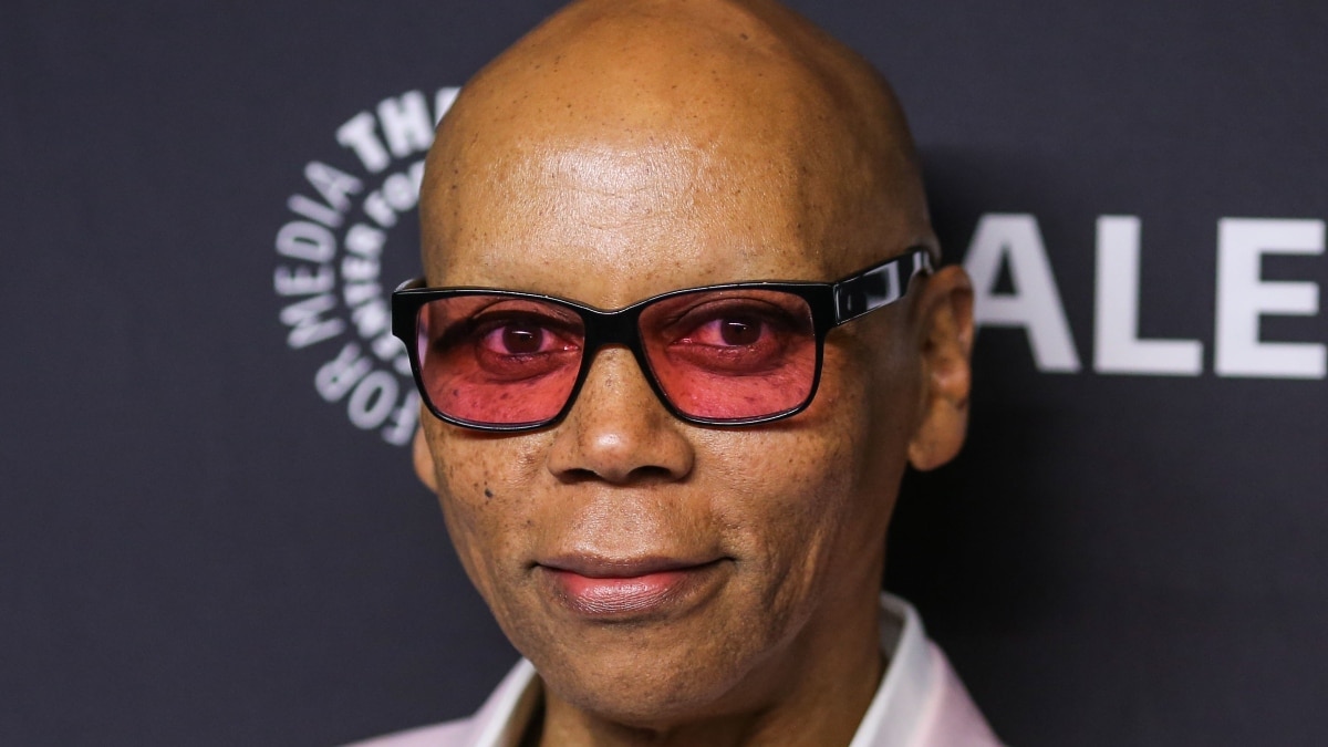 A close-up photo of Rupaul in a white, button-down shirt and pink blazer.