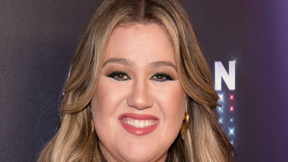 A close up photo of Kelly Clarkson smiling on the runway before her new double-single dropped.