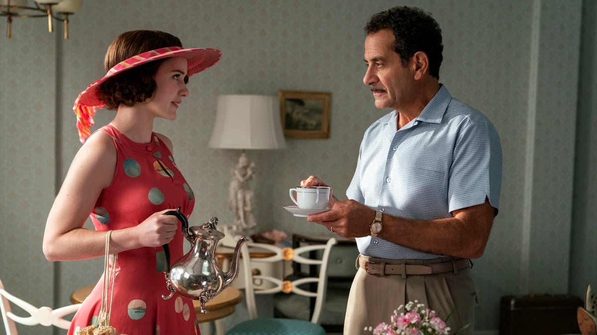 Rachel Brosnahan as Miriam, (Midge) Maisel is holding a teapot and conversing with, and Tony Shalhoub as Abe Weissman who is holding a teacup, in the Prime Video series, The Marvelous Mrs. Maisel.