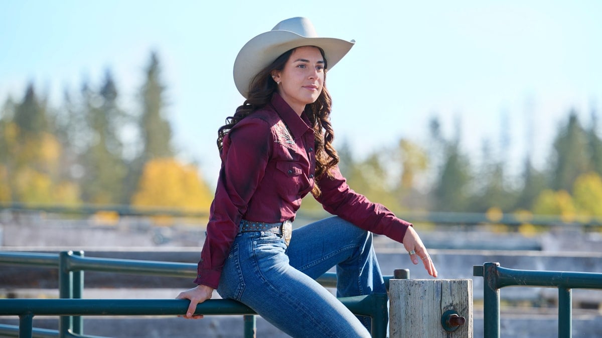 Sara Garcia as Valeria Galindo is sitting on a coral gatem in the Hallmark series, Ride.