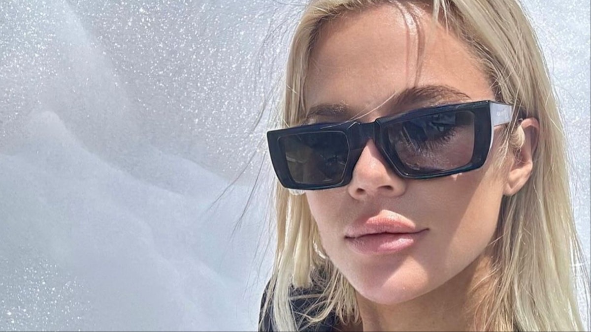 Khloe Kardashian sorride fuori e indossa occhiali da sole.